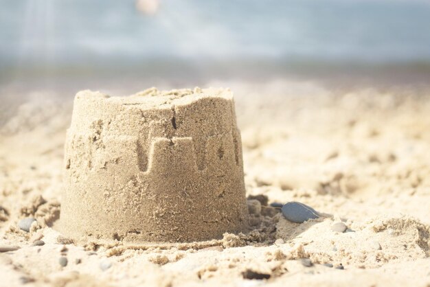 Zbliżenie małego zamku z piasku na plaży pod słońcem z rozmytym tłem