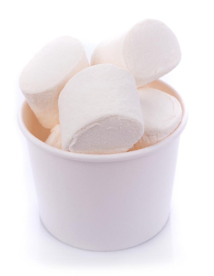 Zdjęcie zbliżenie marshmallows w kubku na białym tle
