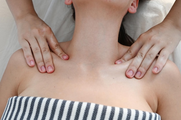 Zdjęcie zbliżenie masażysty wykonuje relaksujący masaż ramion i obojczyków młodej pięknej kobiety w spa