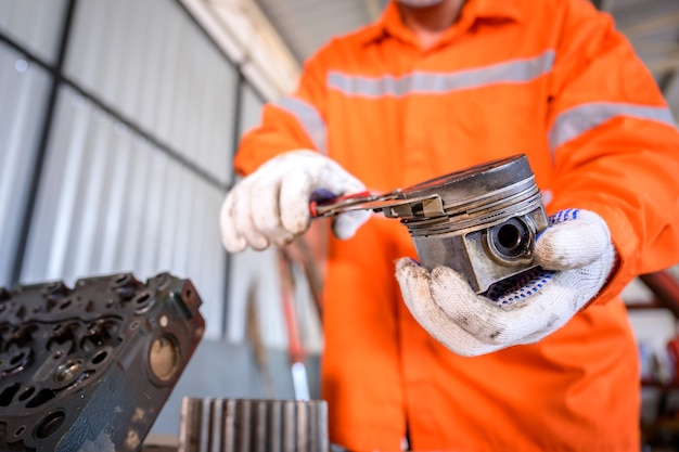 Zbliżenie: mechanik ciągnika Sprawdzanie tłoka ciągnika i usuwanie pierścienia tłokowego Części samochodowe i narzędzia, klucze i ciężki sprzęt garażowy.