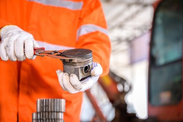 Zbliżenie: mechanik ciągnika Sprawdzanie tłoka ciągnika i usuwanie pierścienia tłokowego Części samochodowe i narzędzia, klucze i ciężki sprzęt garażowy.