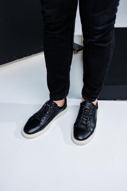 Zbliżenie męskich nóg w czarnych skórzanych trampkach Wygodne męskie buty całoroczne
