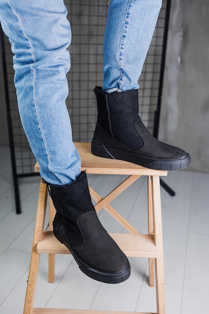 Zbliżenie męskich nóg w dżinsach i czarnych butach zimowych Ciepłe skórzane buty męskie zimowe