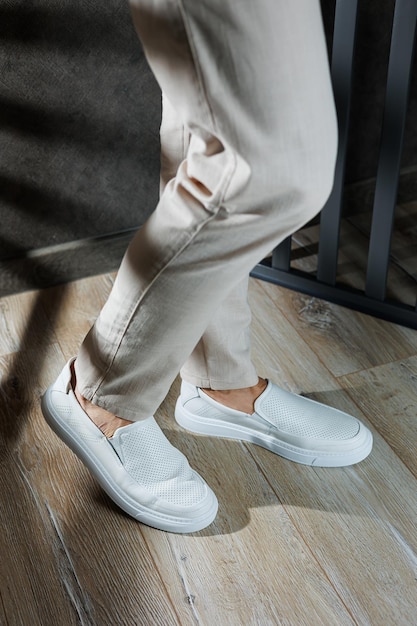 Zdjęcie zbliżenie męskich stóp w białych butach na co dzień modny młody mężczyzna stojący w skórzanych stylowych białych mokasynach w modnych spodniach sezonowe letnie buty męskie casual street style