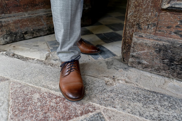 Zbliżenie: męskie nogi w stylowych brązowych butach.
