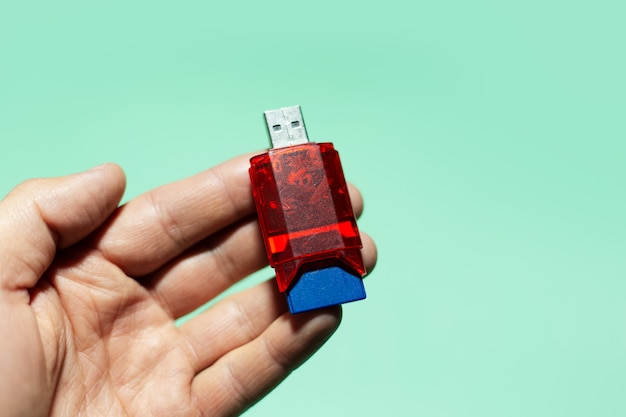 Zbliżenie męskiej ręki trzymającej adapter USB flash do karty SD na białym tle