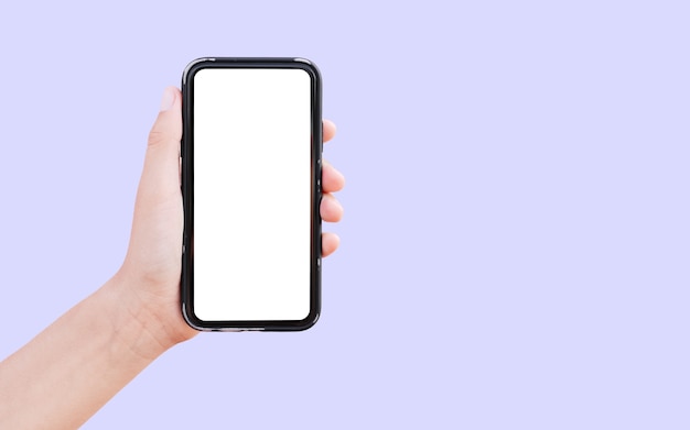 Zbliżenie: męskiej ręki trzymającej smartfon z białą makietą na białym tle na pastelowy fiolet z miejsca na kopię.