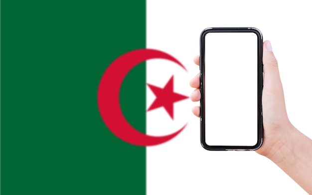 Zbliżenie męskiej ręki trzymającej smartfon z pustym ekranem na tle niewyraźne flaga Algierii