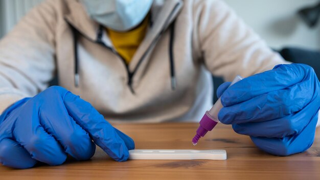 Zbliżenie: mężczyzna umieszczający próbkę w zakraplaczu buforowym do testu na koronawirusa
