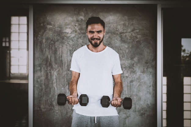 Zbliżenie mężczyzna zdrowego mienia dumbbell trening i budynku ciało przy gym sprawnością fizyczną