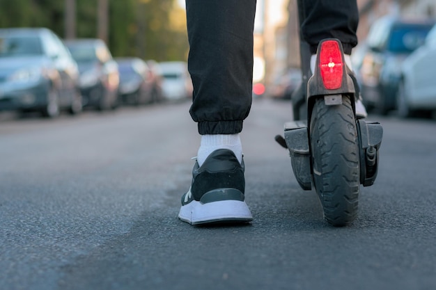 Zbliżenie mężczyzny jadącego na skuterze elektrycznym na ulicy Widok na ziemię