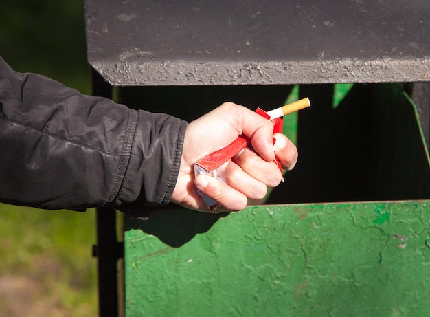 Zdjęcie zbliżenie mężczyzny rzucającego papierosa do kosza na śmieci