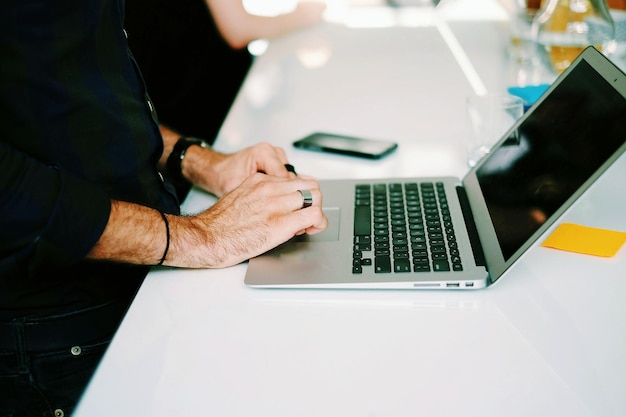 Zdjęcie zbliżenie mężczyzny używającego laptopa na stole