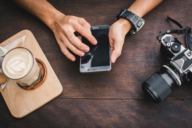 Zdjęcie zbliżenie mężczyzny używającego telefonu z kamerą na stole w kawiarni