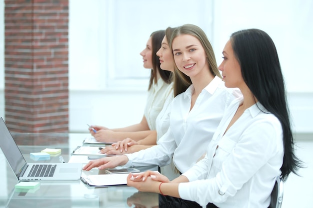 Zbliżenie młoda biznesowa kobieta i współpracownicy siedzący przy biurku