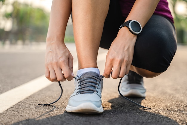 Zbliżenie młoda kobieta biegacz wiąże jej shoelaces. koncepcja zdrowia i fitness.