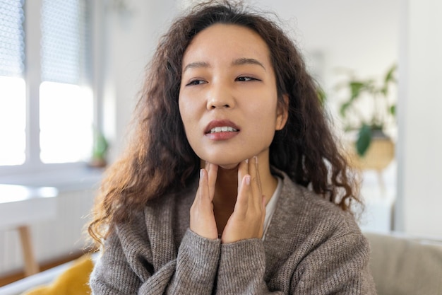 Zbliżenie młodej azjatyckiej kobiety pocierającej zapalenie migdałków problem z zapaleniem migdałków przycięta Kobieta z problemem tarczycy dotykająca szyi dziewczyna ma ból gardła