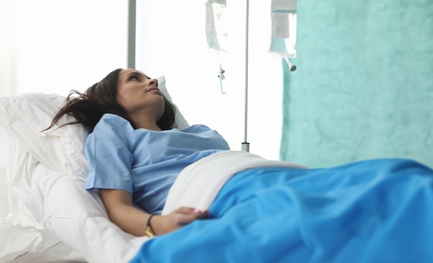 Zbliżenie młodej kobiety leżącej w szpitalnym łóżku i czekającej