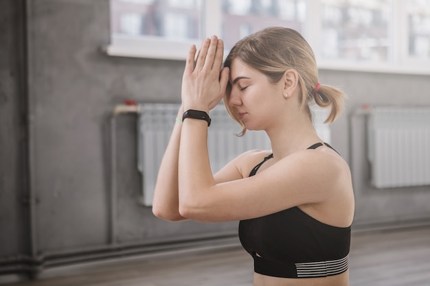 Zbliżenie młodej kobiety wykonującej gest namaste po zrobieniu jogi na siłowni