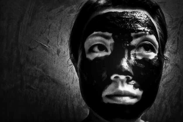 Zdjęcie zbliżenie młodej kobiety z maską na twarzy przy ścianie