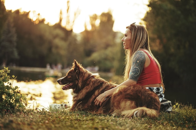 Zbliżenie młodej kobiety z psem siedzącej na trawie w parku