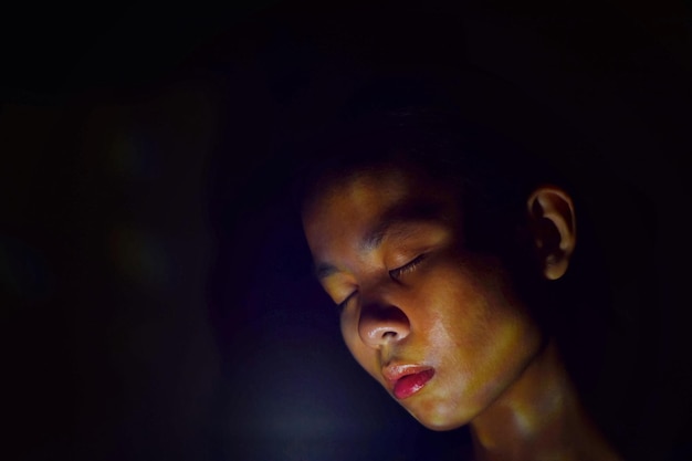 Zdjęcie zbliżenie młodej kobiety z zamkniętymi oczami na czarnym tle