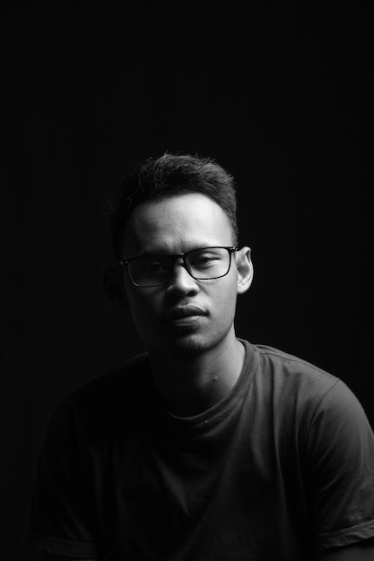 zbliżenie, młody człowiek w okularach na czarno-białym tle. w studiu fotograficznym