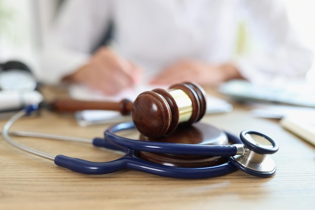 Zbliżenie młotka sędziego i stetoskopu lekarza na biurku za błąd w sztuce lekarskiej