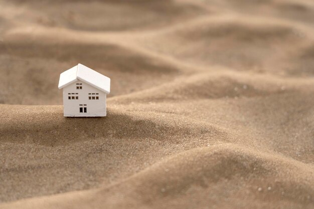 Zbliżenie modelu drewnianego domu na piaszczystej fali