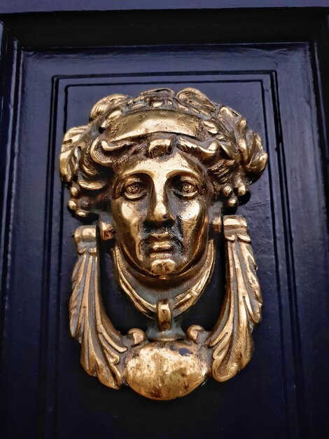 Zbliżenie mosiężnego drzwiaka wykonanego w kształcie kobiecej głowy na gruzińskich czarnych drzwiach irlandzkiego domu w Dublinie w Irlandii.