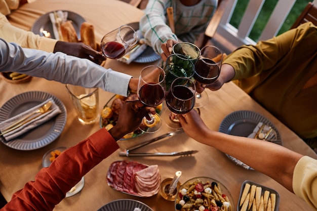 Zbliżenie na afroamerykańską rodzinę brzęczących szklanek przy stole na świeżym powietrzu w przytulnej wieczornej kanapie