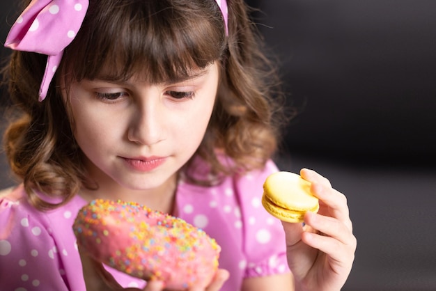 Zbliżenie na atrakcyjną uczennicę na tle domu oblizuje usta, wąchając pączki i makaroniki