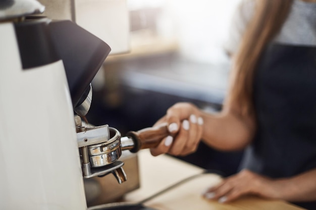 Zbliżenie na baristę używającego młynka do kawy do napełniania kolby