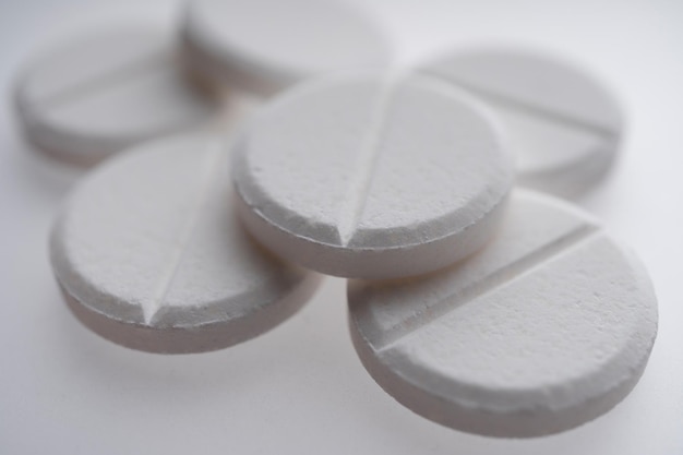 Zbliżenie na białe tabletki na białym tle, medycyna i koncepcja opieki zdrowotnej