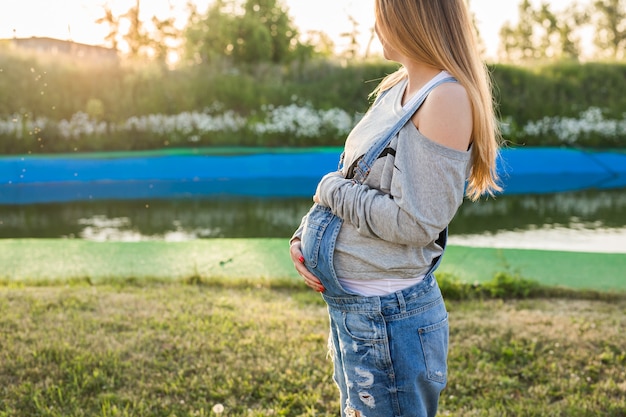 Zbliżenie na brzuchu kobiety w ciąży na zewnątrz, nowa koncepcja życia.