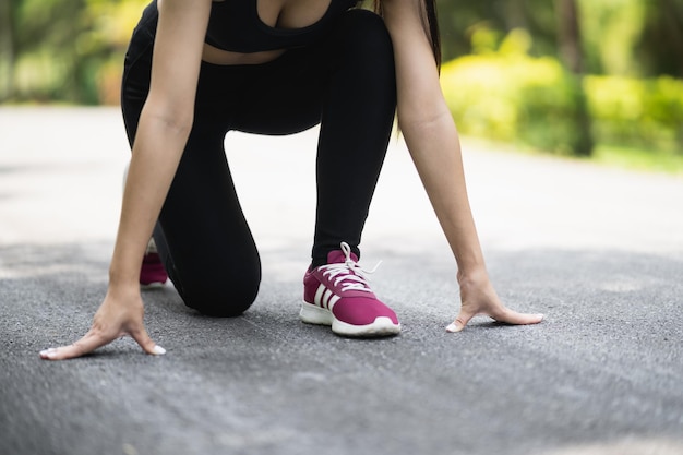 Zdjęcie zbliżenie na buty do biegania lub stopy sportsmenka biegacz pasuje do ciała przed rozpoczęciem biegania lub joggingu w ogrodzie ma więcej drzew i czystego powietrza ćwicząc w parku sport zdrowej koncepcji biegania