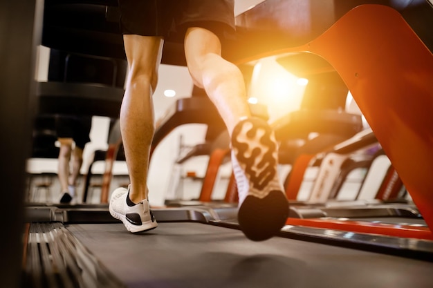 Zbliżenie na buty młody człowiek w odzieży sportowej bieganie na bieżni maszynowej w siłowni fitness koncepcja ćwiczeń fitness i zdrowego stylu życia