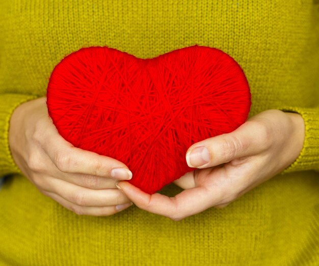 Zdjęcie zbliżenie na czerwonym sercu wykonanym z wełny w ręku kobiety obraz dnia walentynek