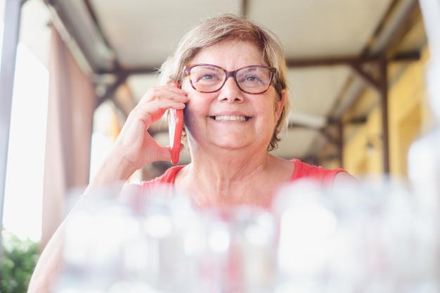Zbliżenie na dojrzałą kobietę siedzącą przy stole w restauracji podczas rozmowy przez telefon komórkowy