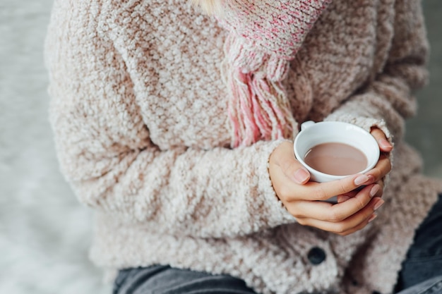 Zdjęcie zbliżenie na dziewczynę w zimowych ubraniach trzymającą filiżankę gorącej czekolady