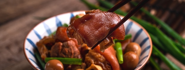 Zbliżenie na jedzenie golonka tajwańska żywności w misce z pałeczkami na rustykalnym stole