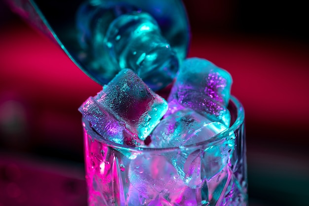 Zbliżenie na koktajl alkoholowy, napój, napój, szklankę pełną lodu w wielobarwnym neonowym świetle