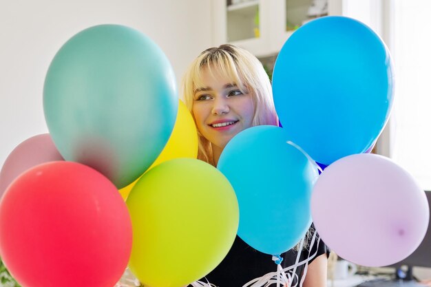 Zbliżenie na kolorowe balony i szczęśliwą uśmiechniętą twarz blond nastolatki