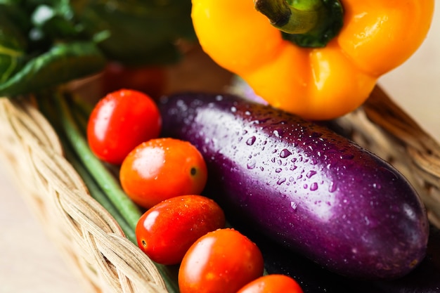 Zbliżenie na kolorowe świeże warzywa w wiklinie rattanowej na drewnianym stole