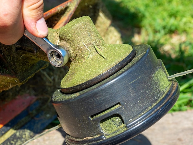 Zdjęcie zbliżenie na kosiarkę do trawy śruba na skrzyni biegów odkręcana kluczem konserwacja sprzętu smarowanie skrzyni biegów