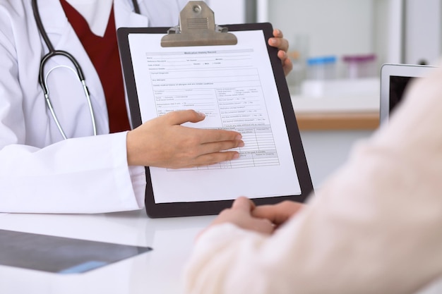 Zbliżenie na lekarkę wskazującą na formularz zgłoszeniowy podczas konsultacji z pacjentem