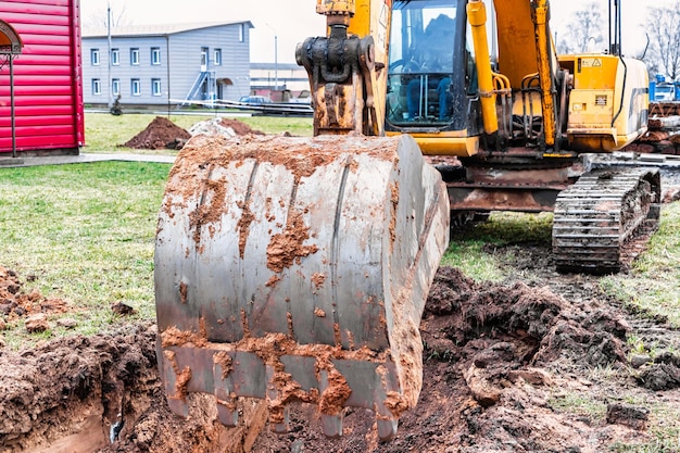 Zbliżenie na łyżkę koparki na placu budowy Koparka kopie rów pod instalacje podziemne Sprzęt budowlany do robót ziemnych