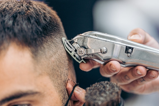 Zbliżenie na maszynę do golenia włosów dorosłego klienta rasy kaukaskiej w zakładzie fryzjerskim