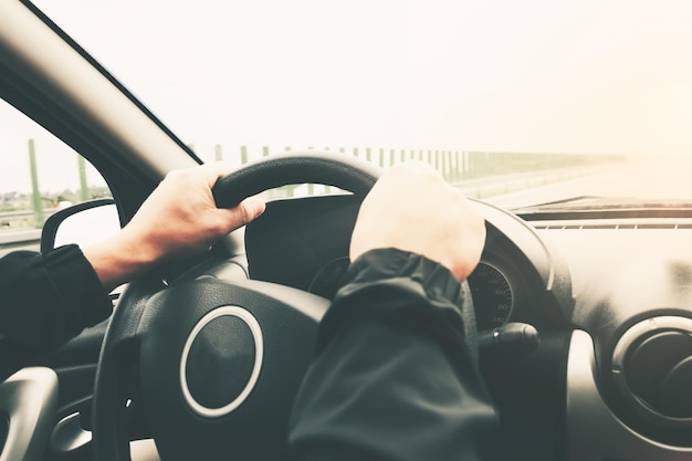 Zbliżenie na męskich rękach na kierownicy samochodu na rozmytym tle autostrady Obraz z efektem vintage zmodyfikowanych dźwięków