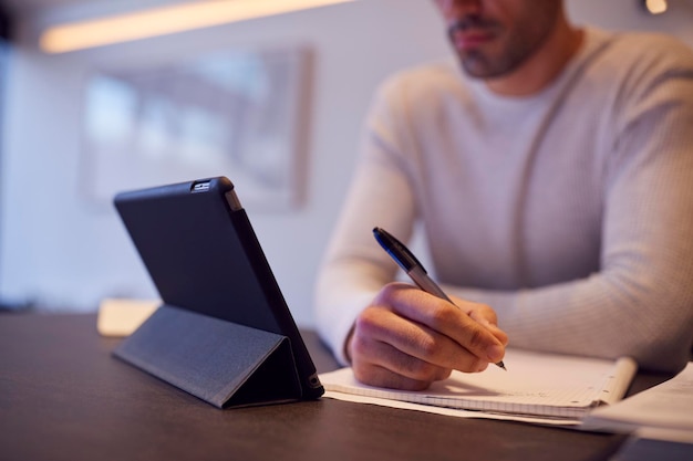 Zbliżenie na mężczyznę w kuchni, pracującego lub studiującego w domu za pomocą cyfrowego tabletu